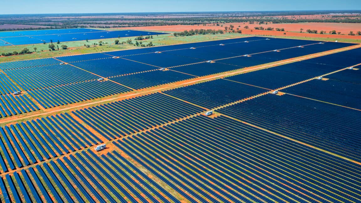 image of a red, dusty scrubland covered in row after row of photovoltaic panels.