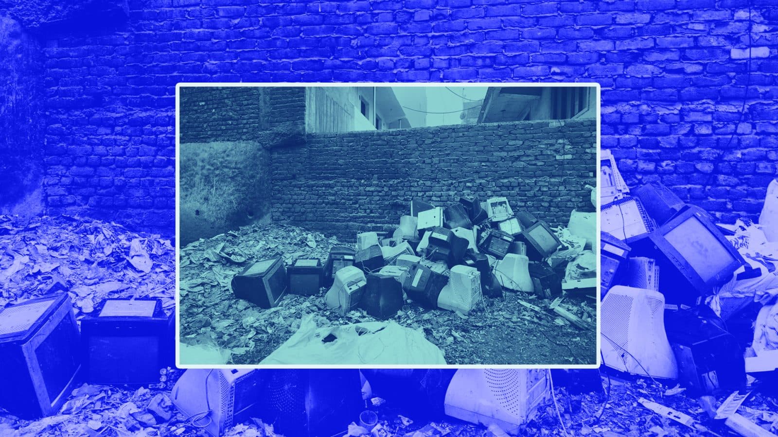 A pile of old, discarded televisions surrounded by garbage near a brick wall.