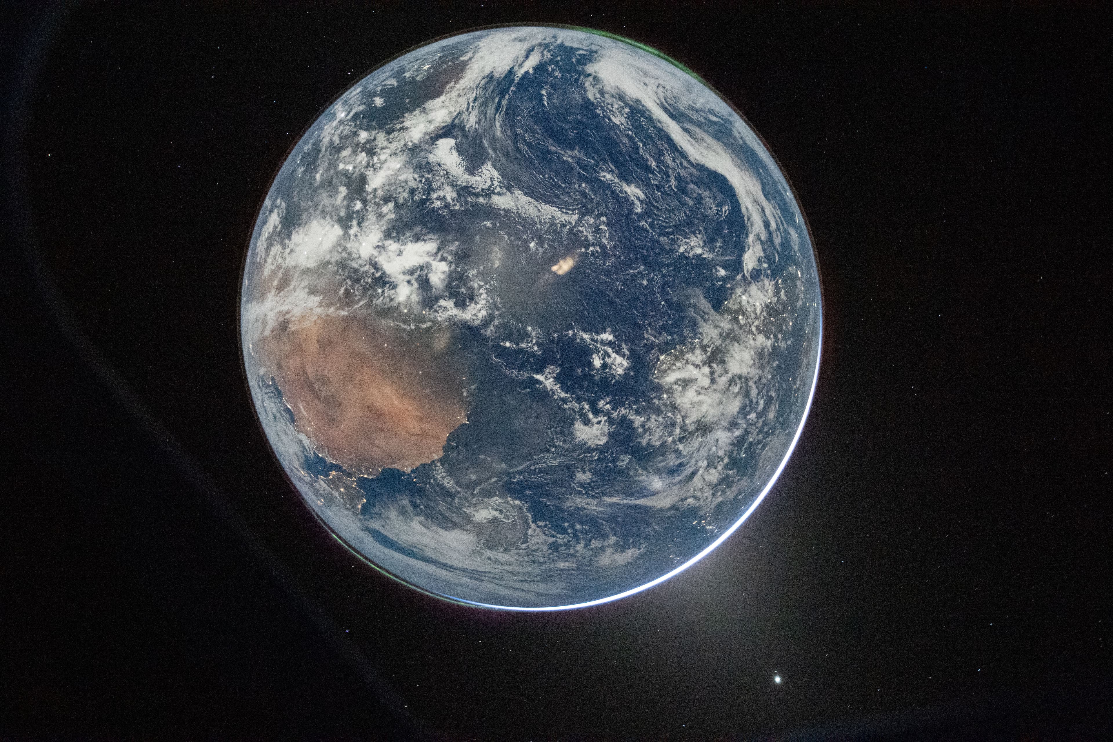 A view of Earth taken by NASA astronaut and Artemis II Commander Reid Wiseman from the Orion spacecraft's window. The image features two auroras (top right and bottom left) and zodiacal light (bottom right) is visible as the Earth eclipses the Sun.