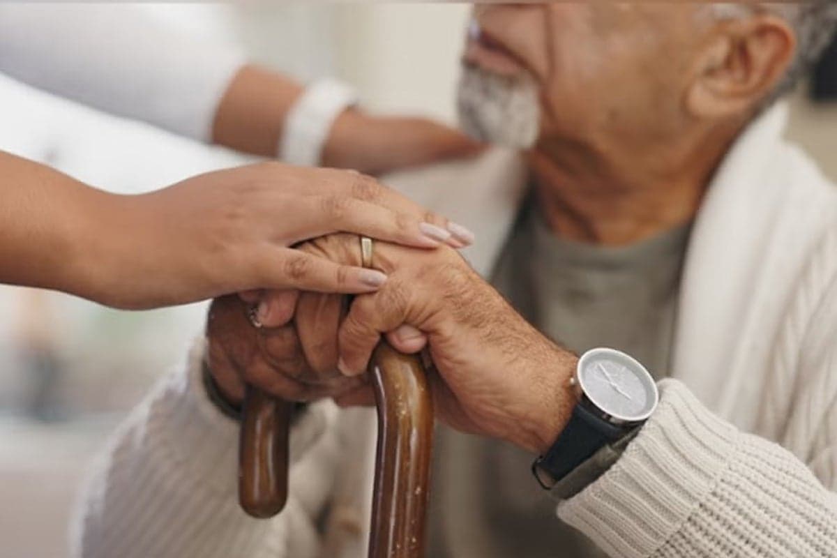 A caregiver steadies a patient using a cane. (via ucf.edu)